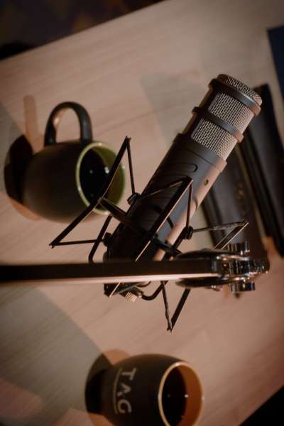 Looking down on a microphone on it's stand, hovering over a table with a mug that says 'TAG'